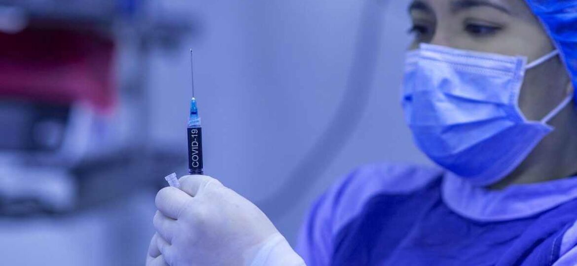 A young female medical professional holds a vaccine.