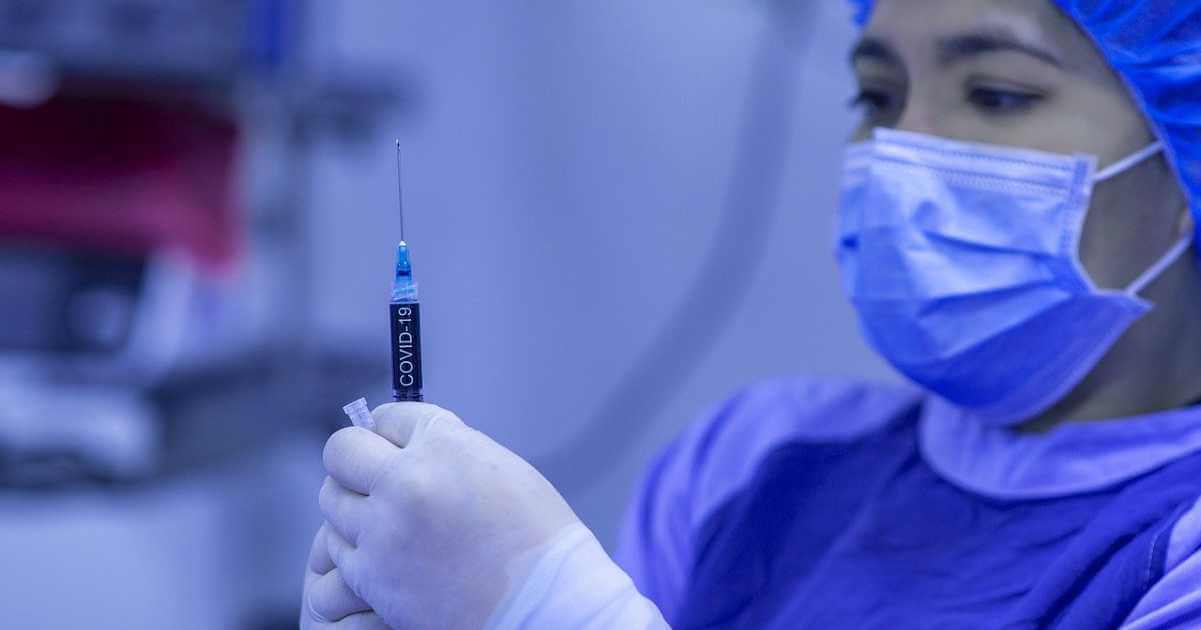 A young female medical professional holds a vaccine.